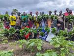 Women hold produce in the community gardnen.